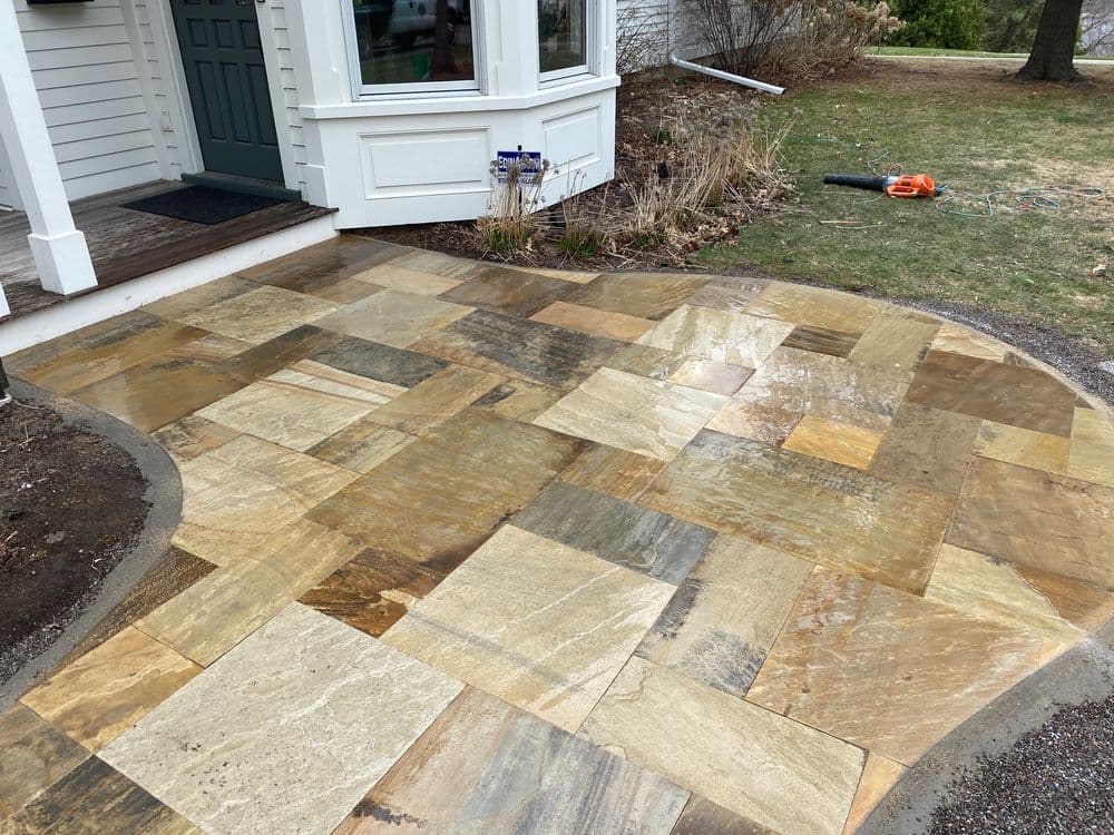 Newly installed stone patio with mixed colors and patterns in a residential outdoor setting.