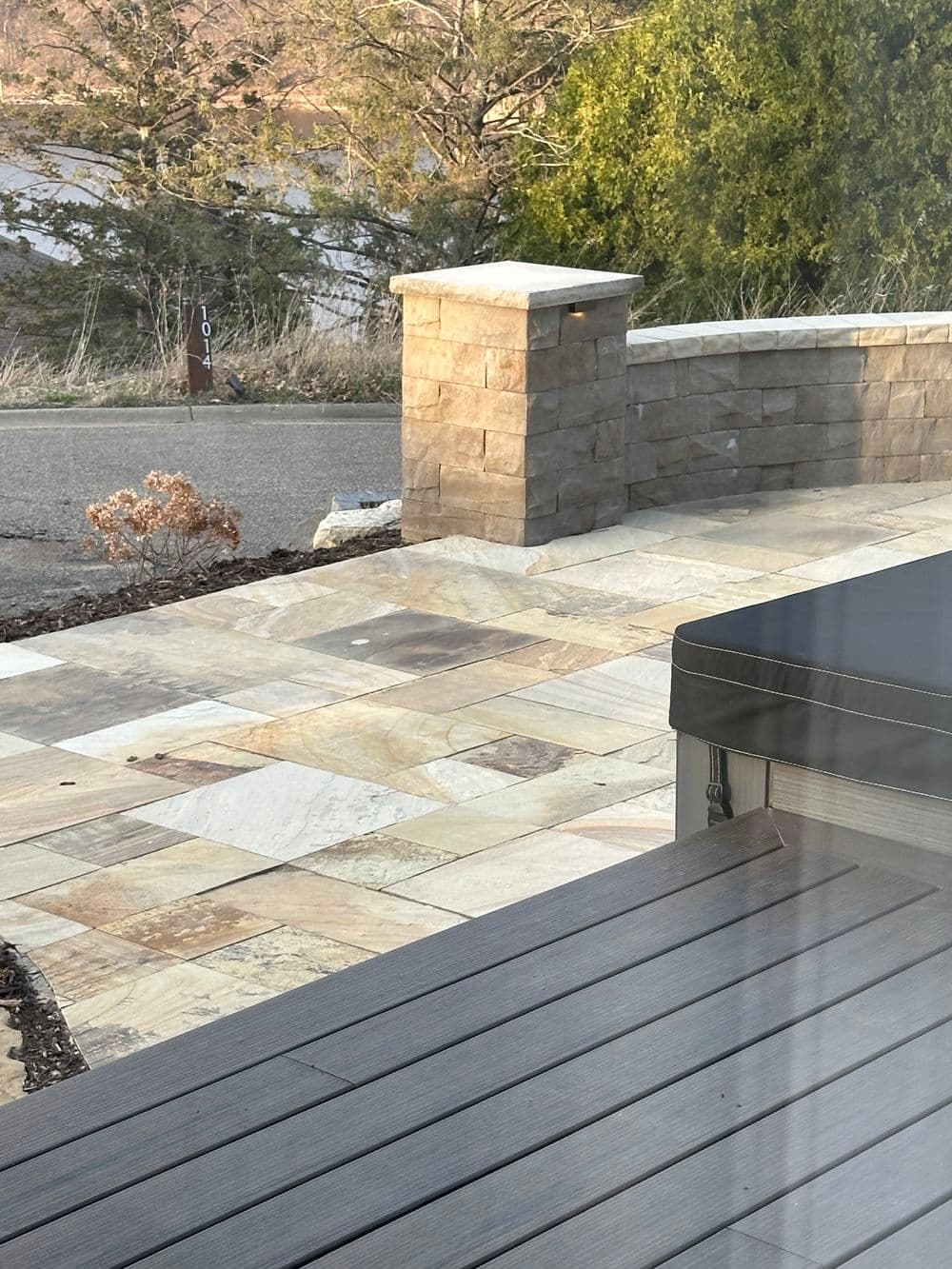 Patio with stone-wall feature and wooden deck overlooking a scenic landscape.