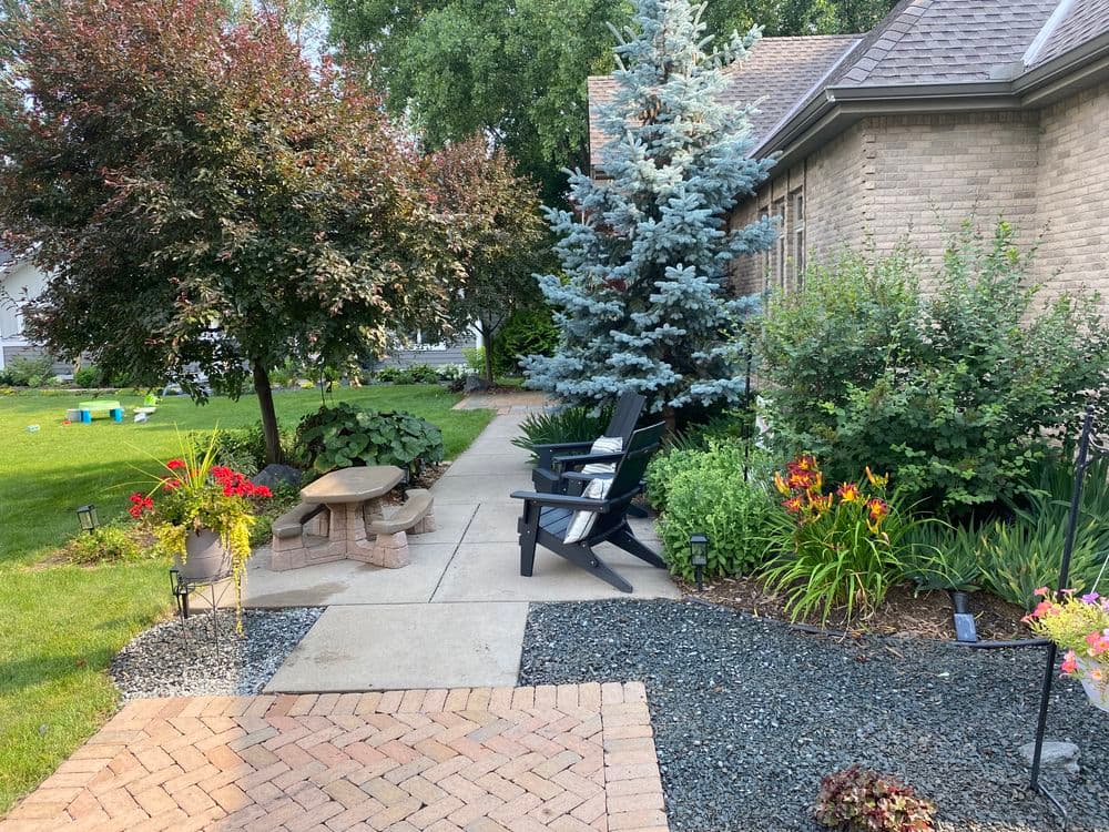 Charming garden with patio chairs, vibrant flowers, and neatly landscaped greenery.