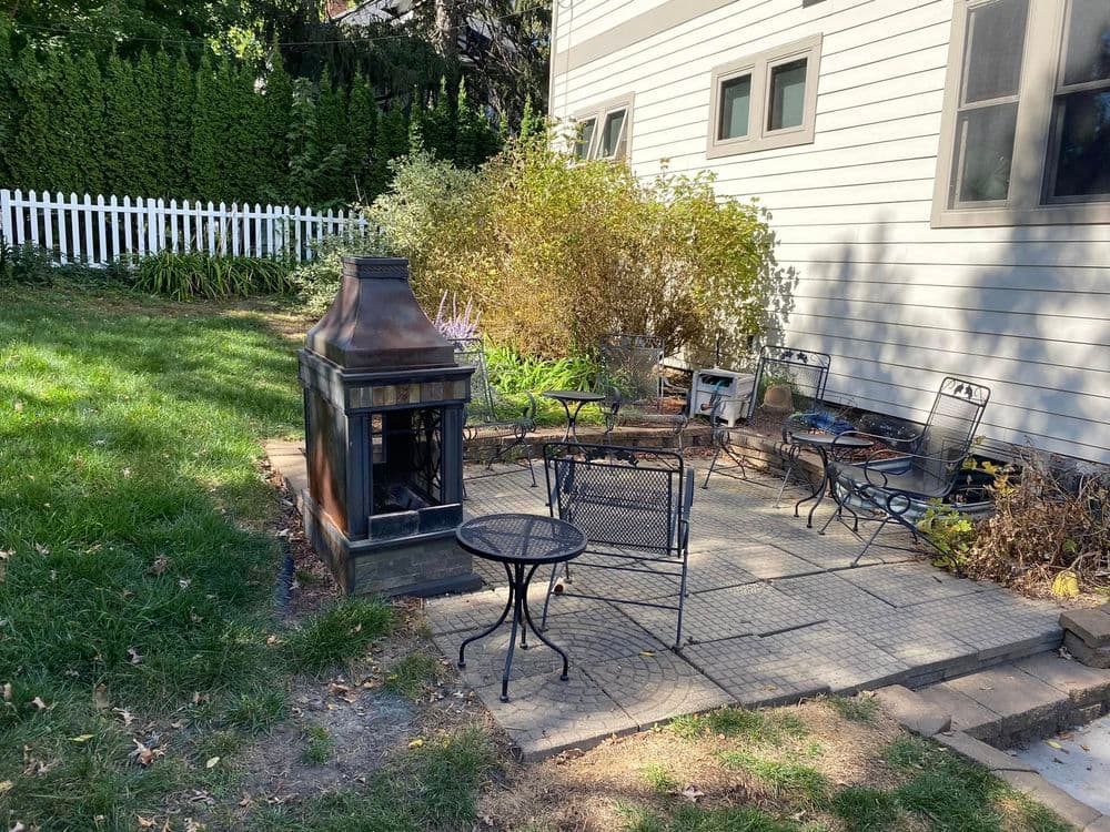 Cozy outdoor seating area with a fire pit and surrounding greenery near a home.