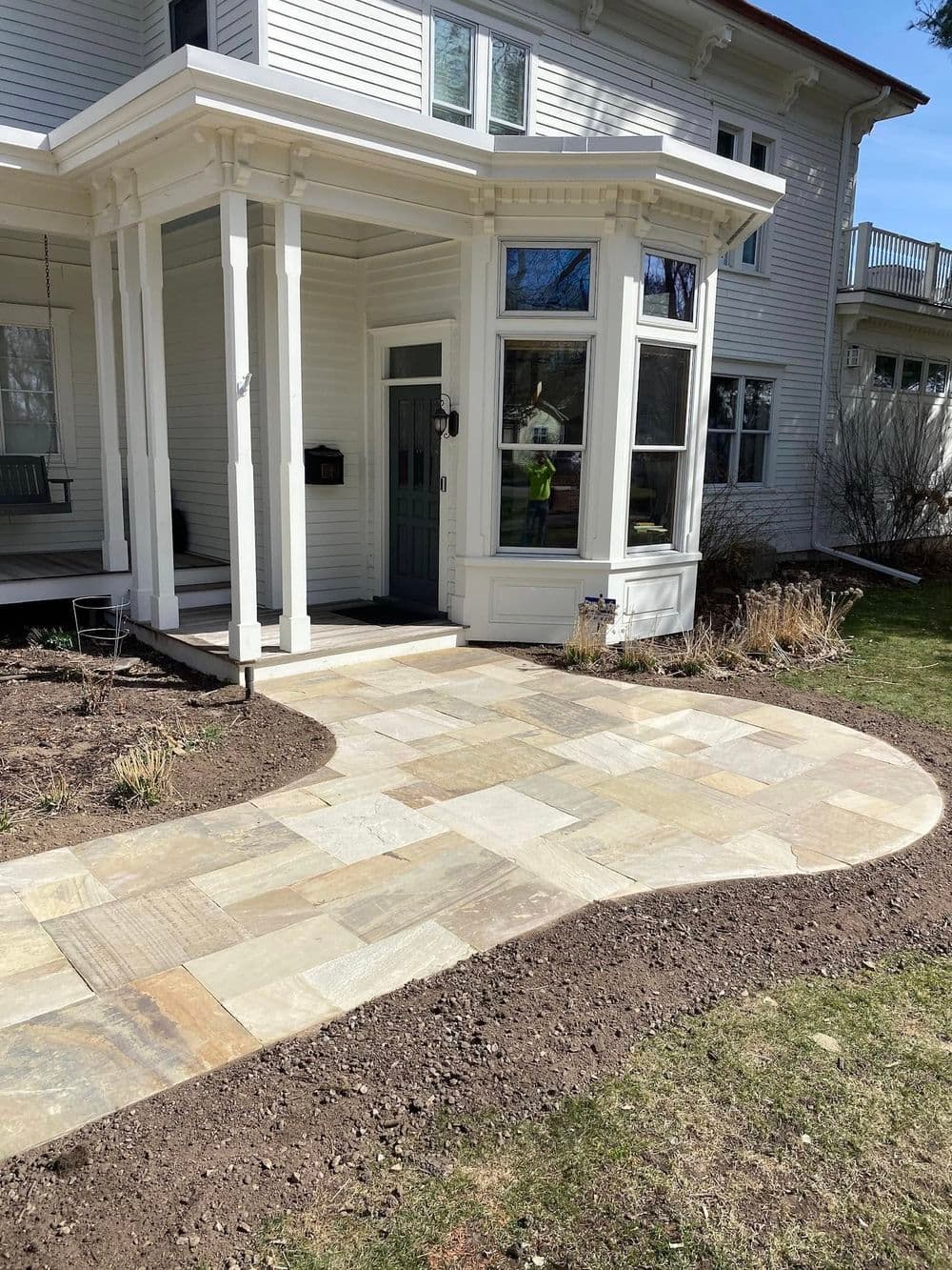 Beautifully landscaped entrance featuring a stone walkway and a classic porch design.